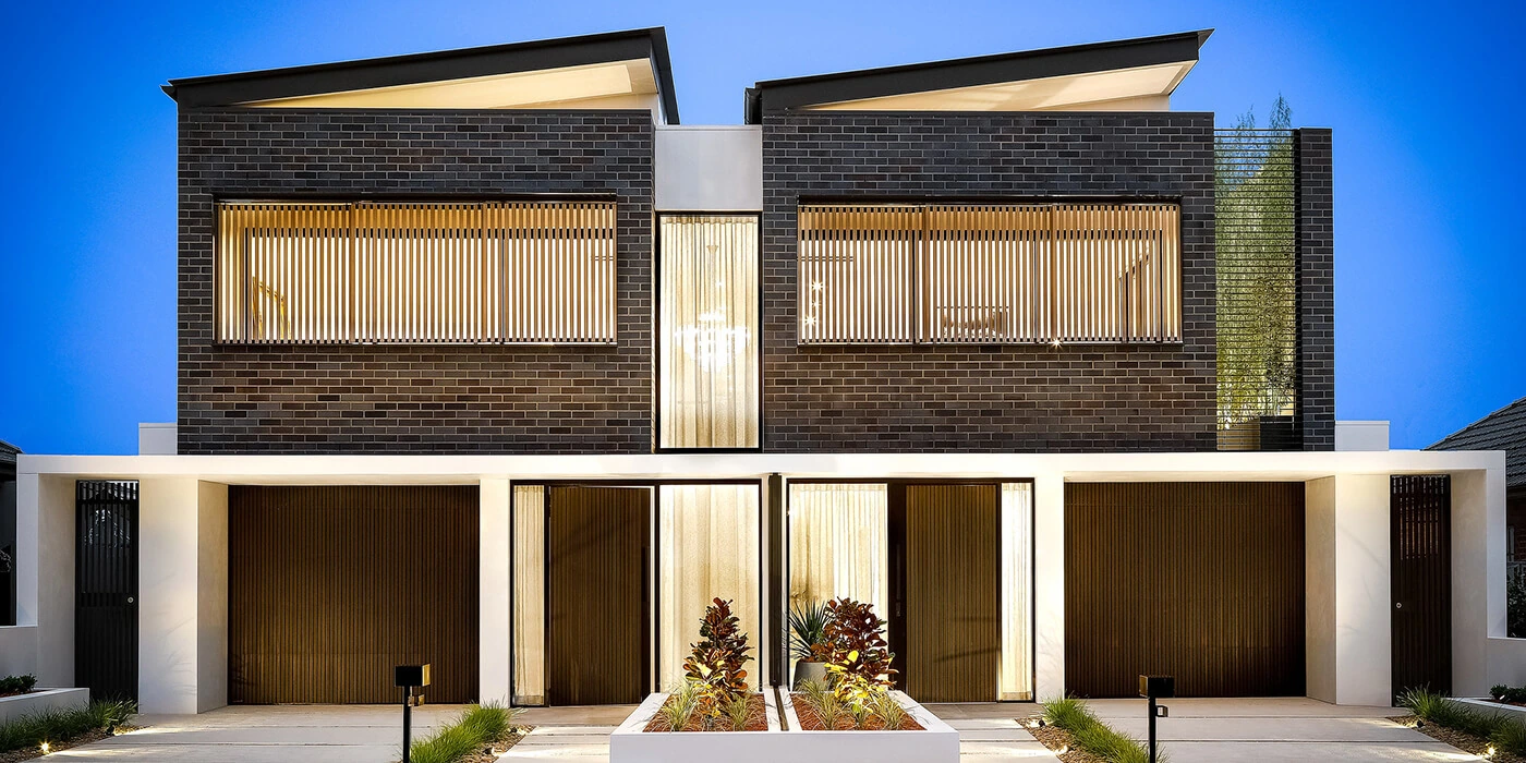 Modern charcoal brick duplex with timber screening and warm lighting